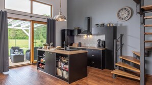 Una cocina moderna con una isla central, estanterías empotradas y una escalera.