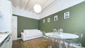 A modern kitchen with white cabinetry, a white dining table with four chairs, and a green accent wall. - Ca d Oro Cozy Suite by Wonderful Italy (Venice)