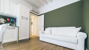 A modern living room with a white sofa, wooden flooring, and a green accent wall. - Ca d Oro Cozy Suite by Wonderful Italy (Venice)