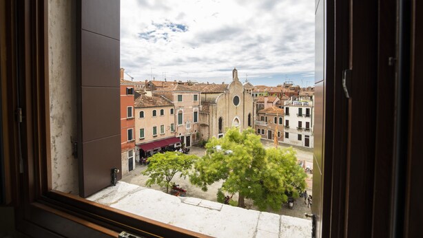 Vista desde una ventana hacia una plaza histórica con edificios y una iglesia destacada.