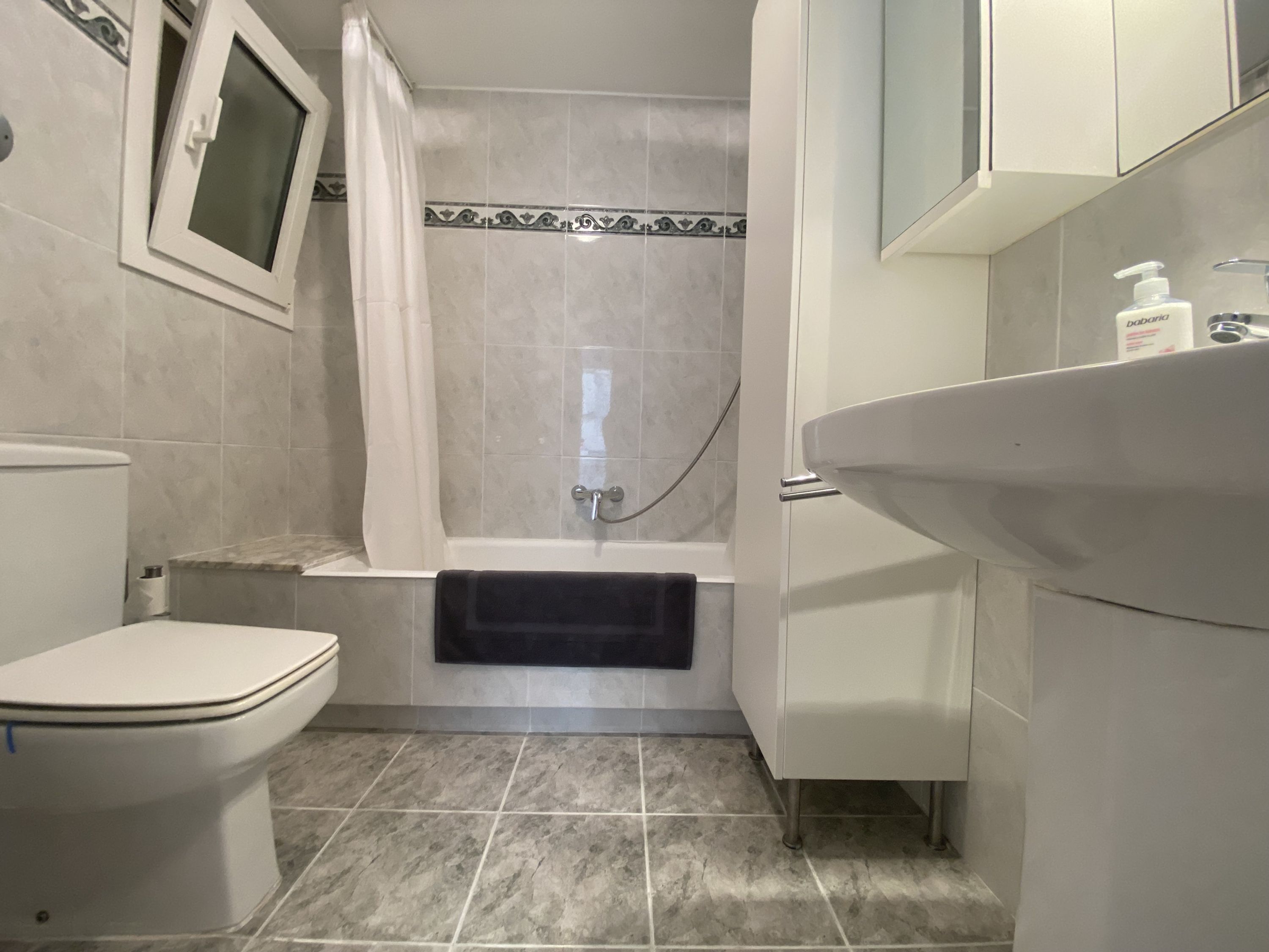 A bathroom with a toilet, bathtub, and sink.