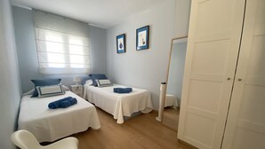 Ένα υπνοδωμάτιο με δύο κρεβάτια, ένα κομοδίνο με ένα φωτιστικό, έναν καθρέφτη και μια ντουλάπα.
