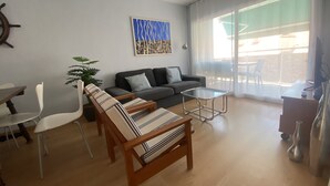Ένα σύγχρονο σαλόνι με έναν καναπέ, ένα τραπεζάκι σαλονιού από γυαλί και μια τραπεζαρία με καρέκλες.