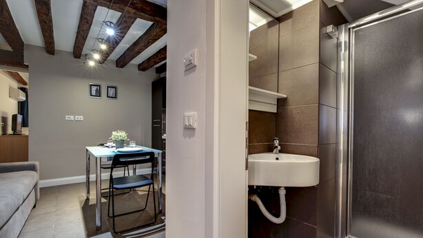 A modern interior with a dining area, a sink, and a shower. - San Giacomo Apartment by Wonderful Italy (Venice)