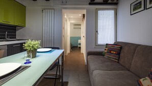 A compact living space with a kitchenette, a dining area, and a seating area with a sofa and a window. - San Giacomo Apartment by Wonderful Italy (Venice)
