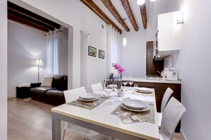 A dining area with a table set for four, a sofa, a lamp, and a kitchen in the background. - Ca dei Botteri 2 by Wonderful Italy (Venice)