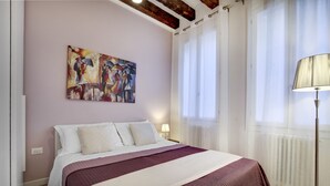 A bedroom with a bed, a painting on the wall, a floor lamp, and a window with curtains. - Ca dei Botteri 2 by Wonderful Italy (Venice)