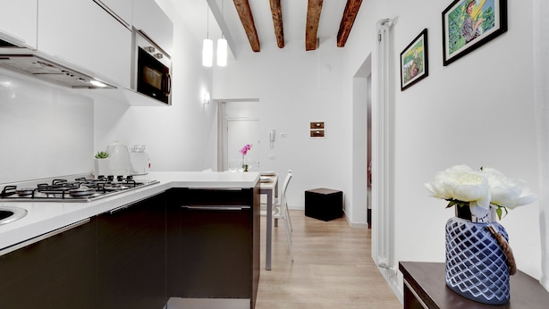 A modern kitchen with a central island, white cabinetry, and a built-in microwave. - Ca dei Botteri 2 by Wonderful Italy (Venice)