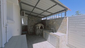 Eine Außenküche mit Steinofen, Spüle und überdachter Terrasse.