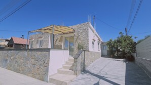 Ein zweigeschossiges Steinhaus mit überdachter Terrasse, einer Steinsäule und einem gepflasterten Auffahrt.