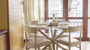 A dining area with a glass table, white chairs, and a hanging pendant light. - Sansoni Palace by Wonderful Italy (Venice)