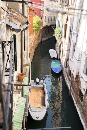 A narrow canal with boats, buildings on either side, and a view of the waterway.