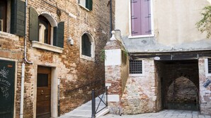 A narrow alleyway with a brick building, a wooden door, and a small staircase leading to a second floor. - Sansoni Palace by Wonderful Italy (Venice)