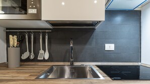 A modern kitchen with a stainless steel sink, an induction cooktop, and wooden countertops. - Accademia II by Wonderful Italy (Venice)