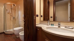 Ein Badezimmer mit Duschkabine aus Glas, einer weißen Toilette, einem Waschbecken mit Spiegel und Holzschränken.
