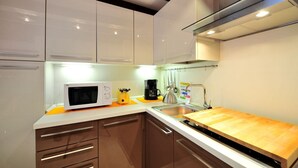 A modern kitchen with white cabinets, a microwave, a coffee maker, and a wooden countertop.