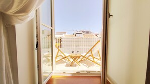 A corridor leading to a balcony with a view of buildings and a crane in the distance.