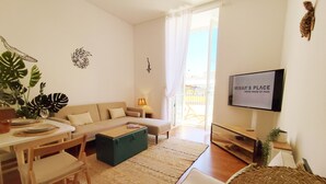 A living room with a sofa, coffee table, TV, and a view of the outside.