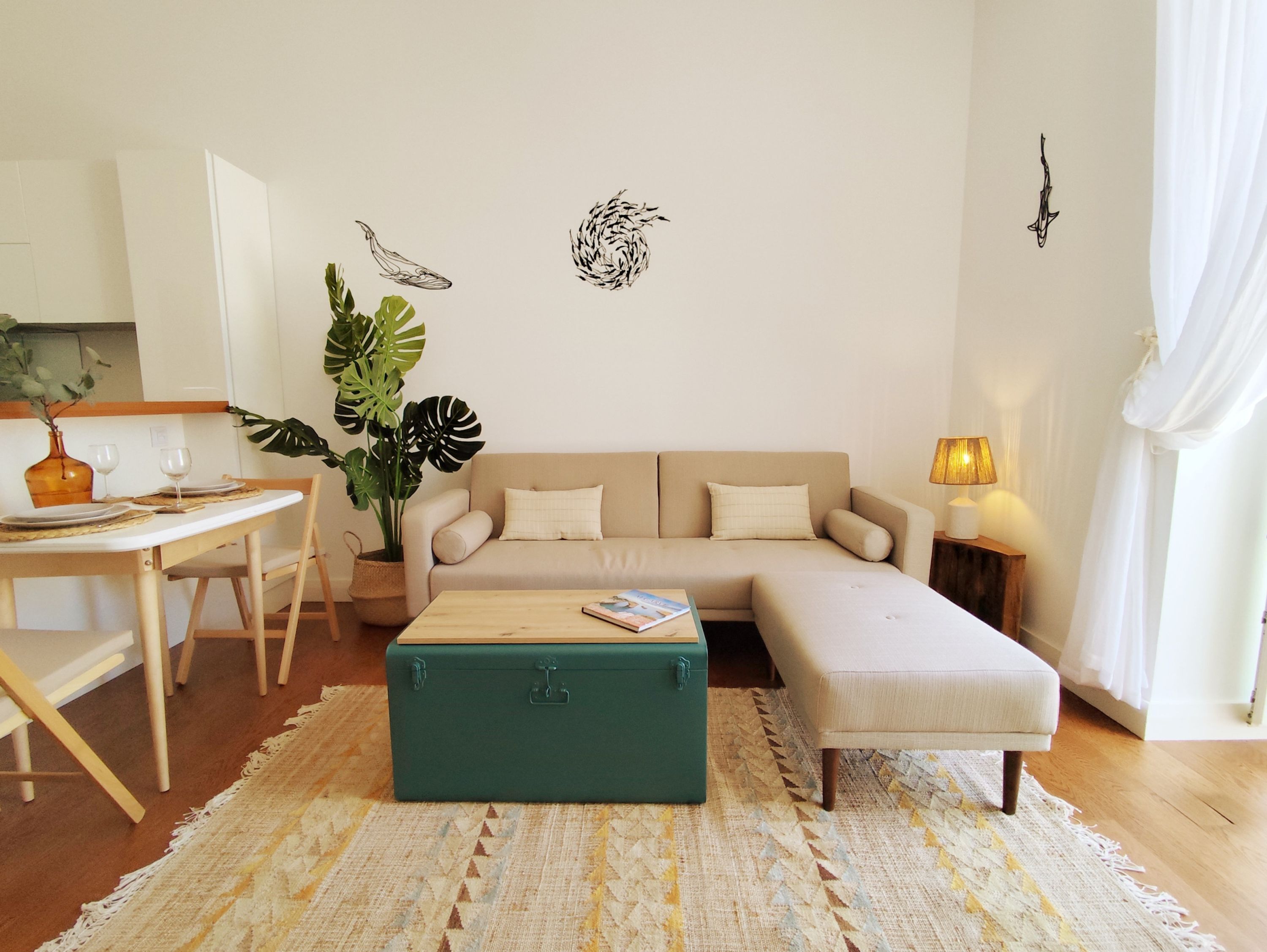 Un salon comprenant un canapé, une table basse, une table à manger avec des chaises, une plante et des œuvres d’art murales.