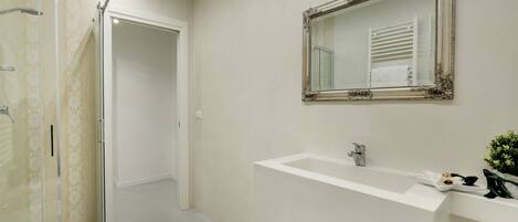 A bathroom with a shower, a sink, and a mirror.