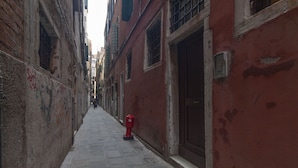 A narrow alleyway with a red fire hydrant, stone walls, and a door on the right. - Leon D Oro Apartment by Wonderful Italy (Venice)