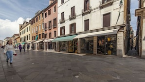 A pedestrian street lined with historic buildings, some with shops and cafes. - Leon D Oro Apartment by Wonderful Italy (Venice)