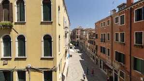 A narrow street lined with historic buildings, featuring arched windows and balconies. - Doge Palace 2 - Locz (Venice)