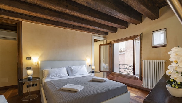 A bedroom with a bed, bedside tables, a window with a view, and a radiator. - Doge Palace 2 - Locz (Venice)
