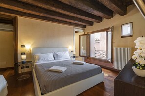 Een slaapkamer met een bed, nachtkastjes, een raam met uitzicht en een radiator.
