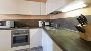 A modern kitchen with white cabinets, stainless steel appliances, and a wooden knife block. - Doge Palace 2 - Locz (Venice)