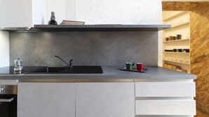 Eine moderne Küche mit einer schwarzen Spüle, einer Kaffeemaschine und einem Regal voller bunter Tassen.