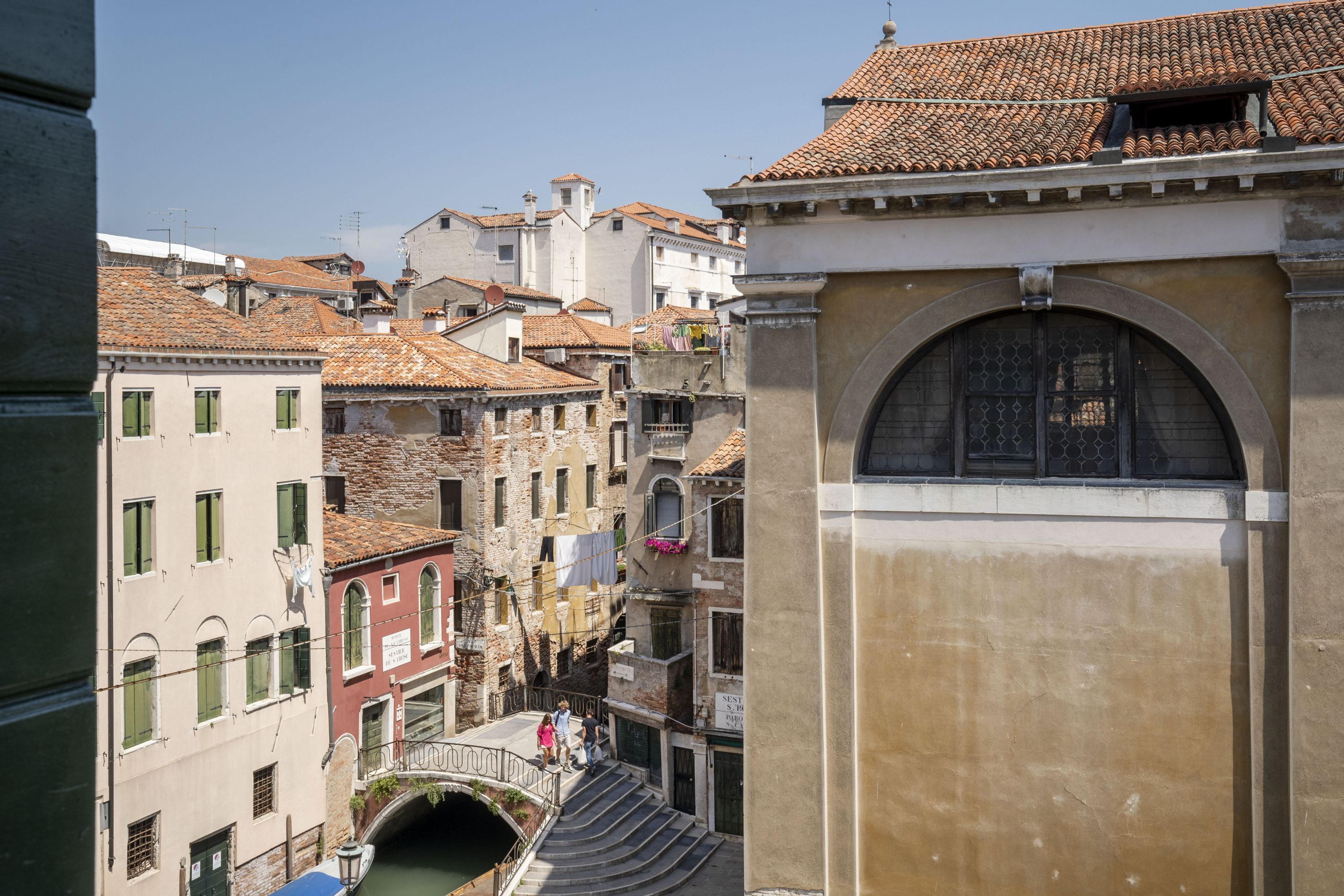 A narrow street with buildings featuring arched windows and tiled roofs.