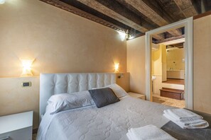 Ein Hotelzimmer mit Bett, Nachttischlampen, einem Nachttisch und Blick auf ein Badezimmer.