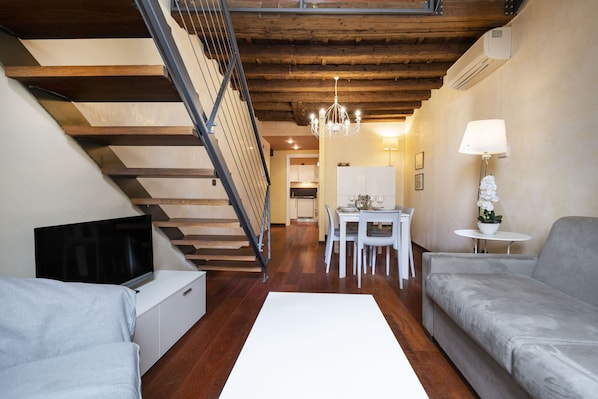 A modern living room with a staircase, a dining area, and a sofa.