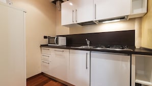 A modern kitchen with white cabinets, a microwave, a sink, and a stove. - Doge Palace 5 - Locz (Venice)