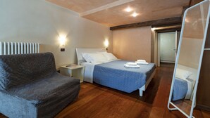 A hotel room with a bed, a chair, a bedside table, and a mirror. - Doge Palace 5 - Locz (Venice)