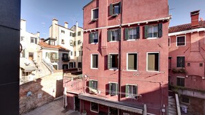 A red building with multiple windows and balconies, a visible staircase, and a clear sky. - Pozzo Roverso by Wonderful Italy (Venice)