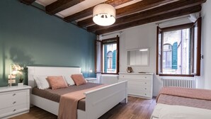Une chambre à coucher avec un lit, des tables de chevet, une commode et une fenêtre avec des volets.