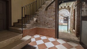 Un escalier dont les marches sont recouvertes d’un motif à carreaux, menant à une pièce d’où l’on peut admirer une cour.