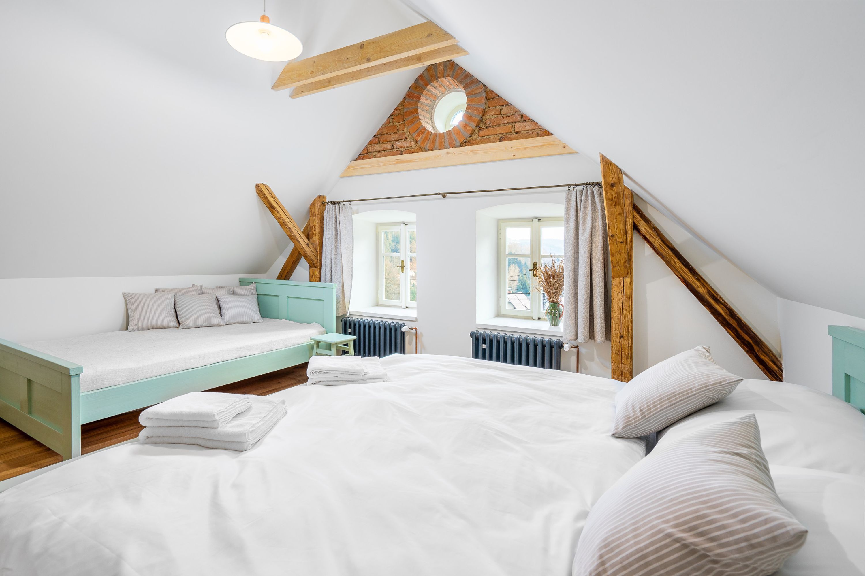 Ein Schlafzimmer mit Hochbett, kleinem Tisch und einem Fenster mit Vorhängen.