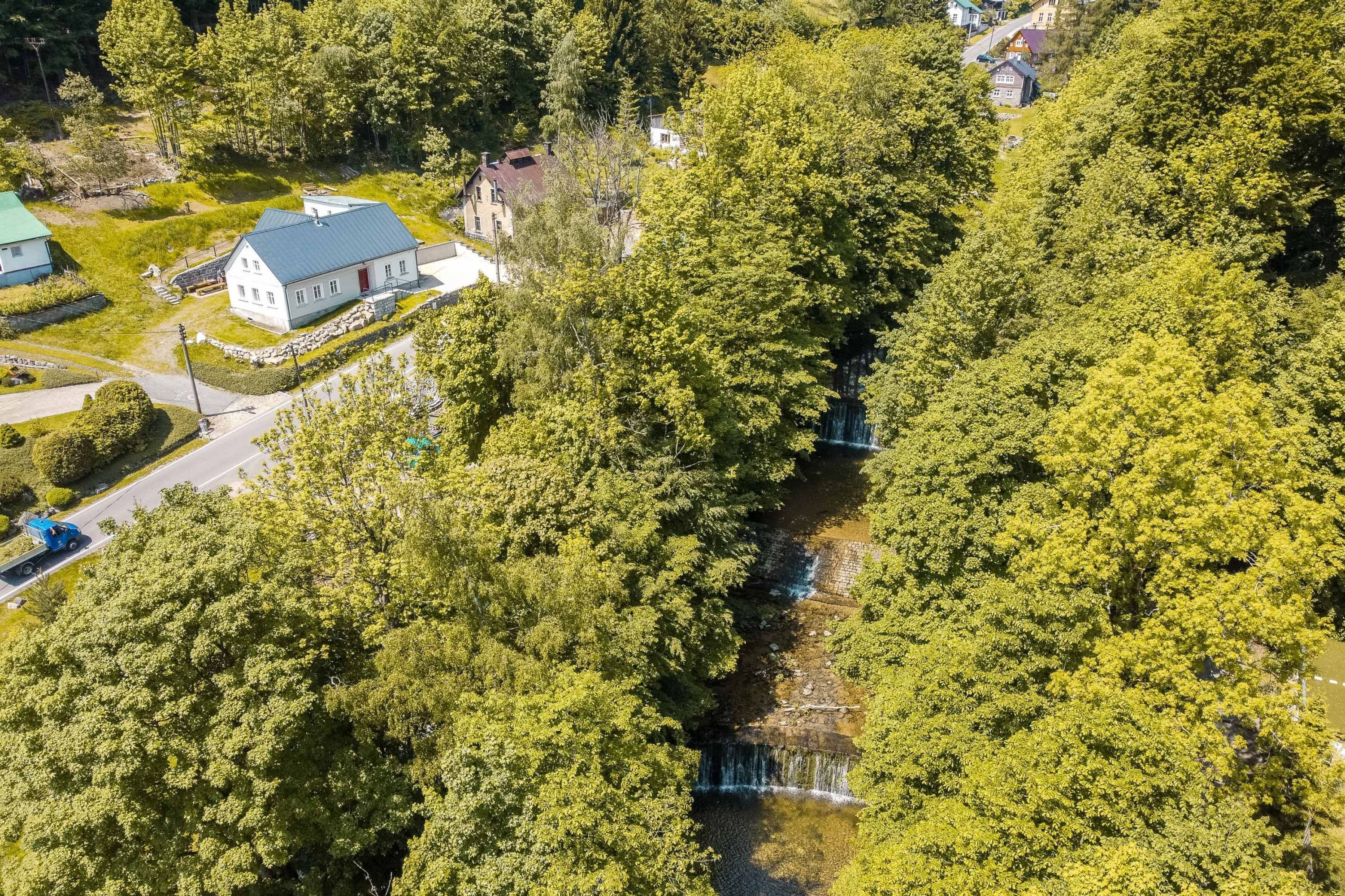 Vue aérienne d’un quartier résidentiel avec une maison, une petite route et une cascade.