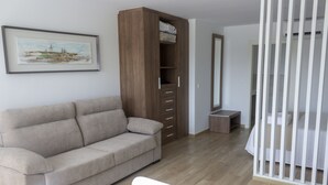 Una sala moderna con un sofá color beige, un mueble de madera y una cuna blanca.