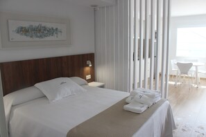 A hotel room with a bed, a nightstand, a wall-mounted lamp, a window, and a view of the outside. - Alén de Louro - Apartamento 2 Area Maior (Lariño)
