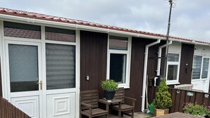 Rivi siirrettäviä asuntovaunuja, joista jokaisella on patio, jossa on puuhuonekaluja ja ruukkukasveja.