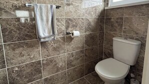 A bathroom with a toilet, a towel rack, and a roll of toilet paper. - Seaside Escape Chalet in Bridlington (Bridlington)