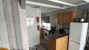 A modern kitchen with wooden cabinets, a built-in oven, and a refrigerator. - Seaside Escape Chalet in Bridlington (Bridlington)