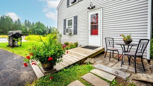 A house with a wooden deck, outdoor seating, and a grill.