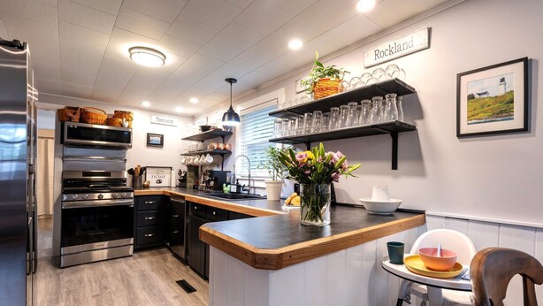 A modern kitchen with a central island, built-in appliances, and a dining area with a high chair.