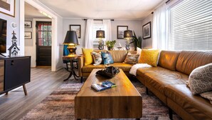 A modern living room with a brown leather sofa, a wooden coffee table, and a black cabinet.