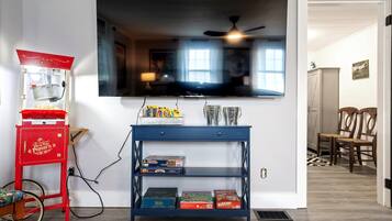 Een woonkamer met een rode popcornmachine, een blauwe entertainmentkast en een flatscreen televisie aan de muur.